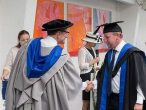 On the right, Christian Berg, CEO Viking Supply Ships, receives his degree.