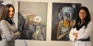 Alina Teodorescu (left) and Michaela Vergottis, with Alina’s acrylic works Parallel Solitudes and Hugging Angels.